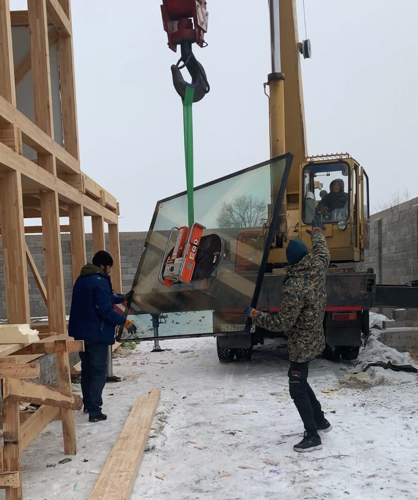 Каркас фахверк-дома из клеёного бруса на плите фундамента, монтажники на площадке в Астане